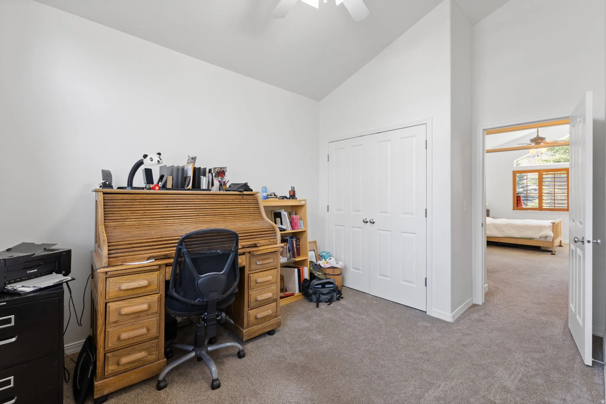Carpeted interior space featuring a double-door closet, vaulted ceiling, and an overhead ceiling fan
