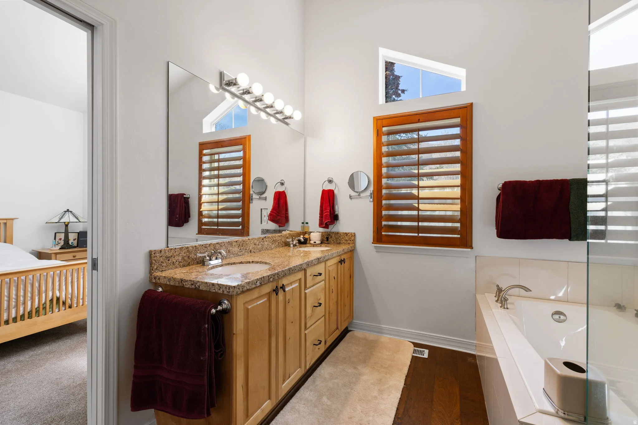 Spacious bathroom featuring a dual vanity with a light-toned countertop, wood-finish cabinetry, and brushed nickel fixtures