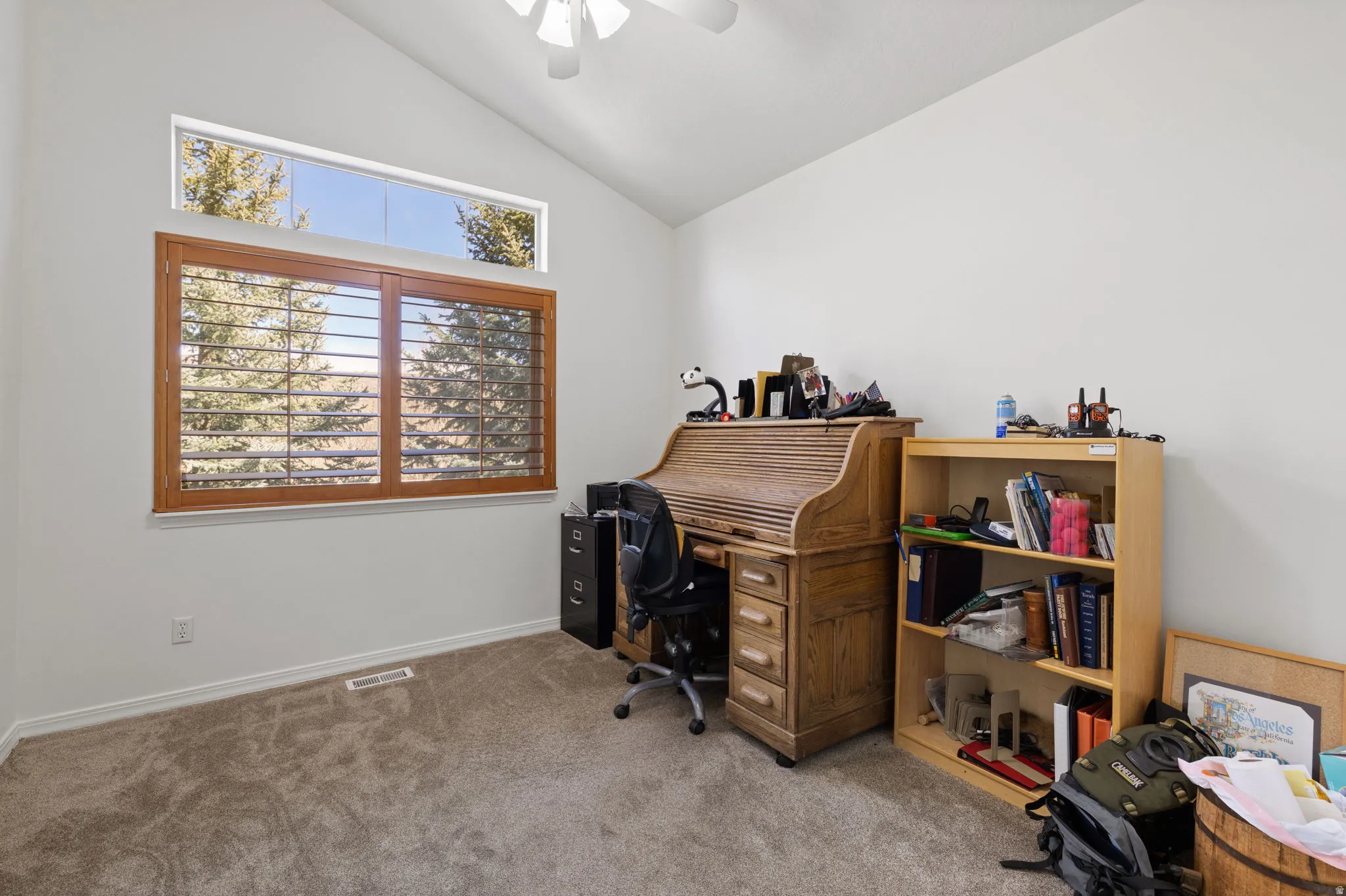 Vaulted ceiling room with an upper transom window and a lower window featuring wood plantation shutters
