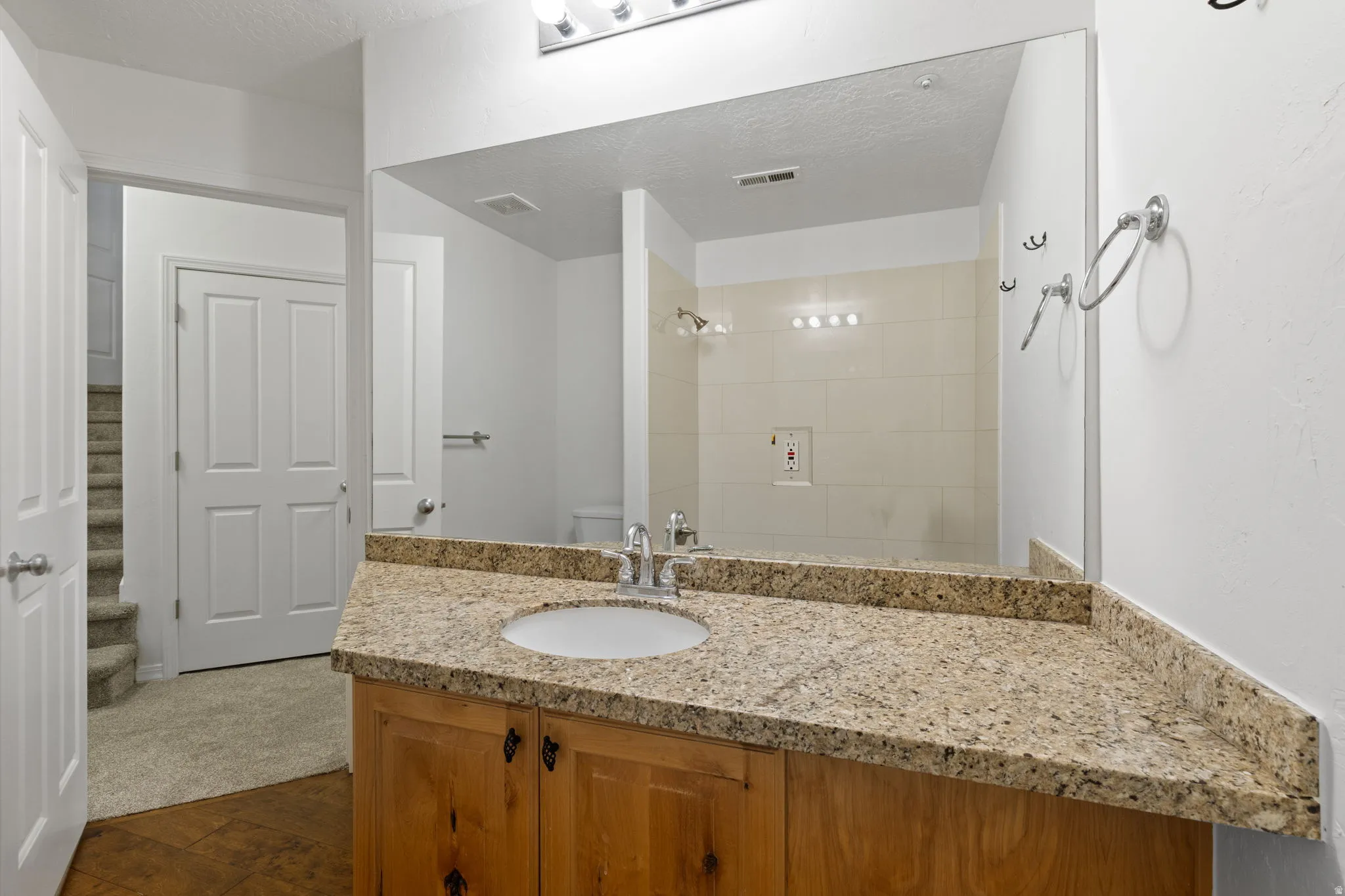 Bathroom vanity featuring a light-toned granite countertop, a single undermount sink, and wood cabinetry
