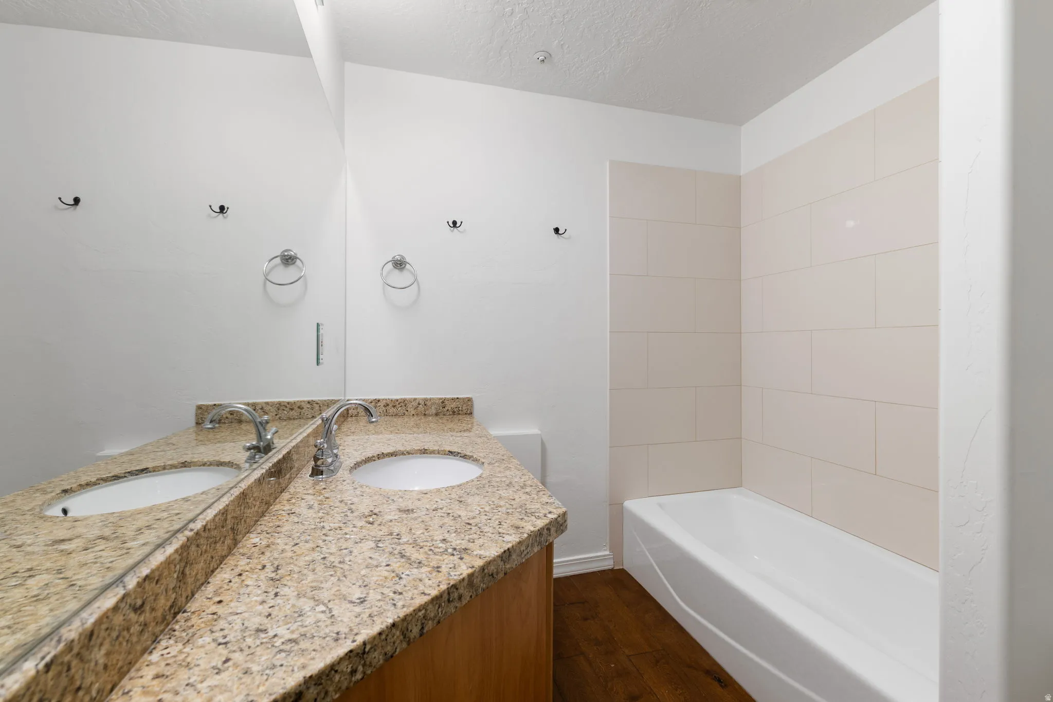 Bathroom featuring a double vanity with granite-style countertop, two undermount sinks, and chrome faucets