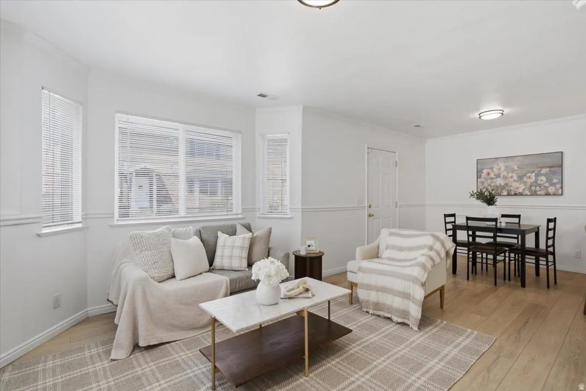 Light wood-finish flooring, white walls with chair rail molding, and multiple windows with horizontal blinds
