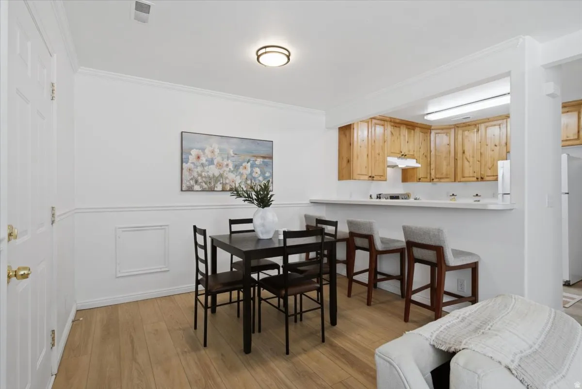Wood-finish flooring throughout, bright white walls with wainscoting, and crown molding