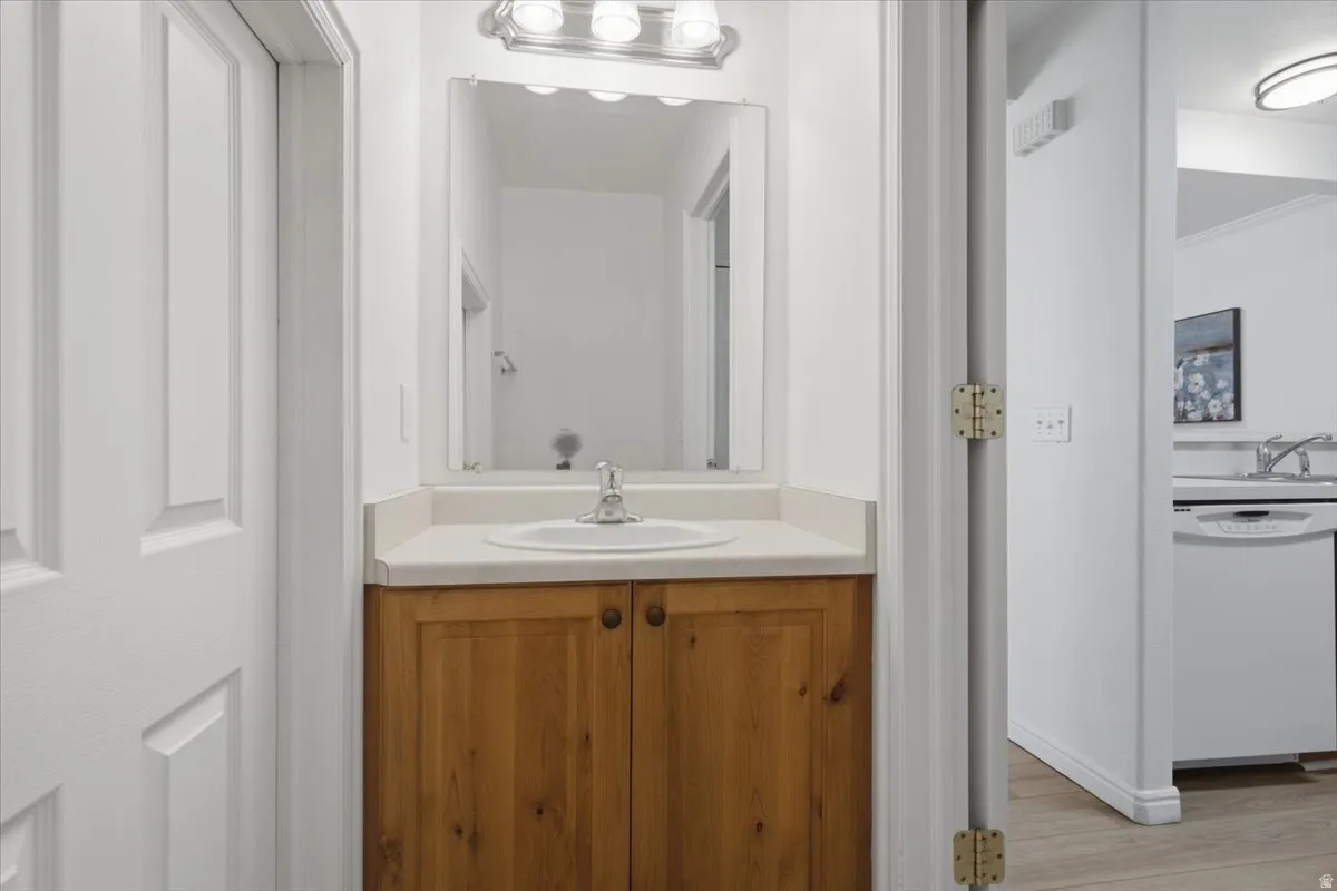 Wood-finish vanity with a single basin sink and a mirror with overhead lighting