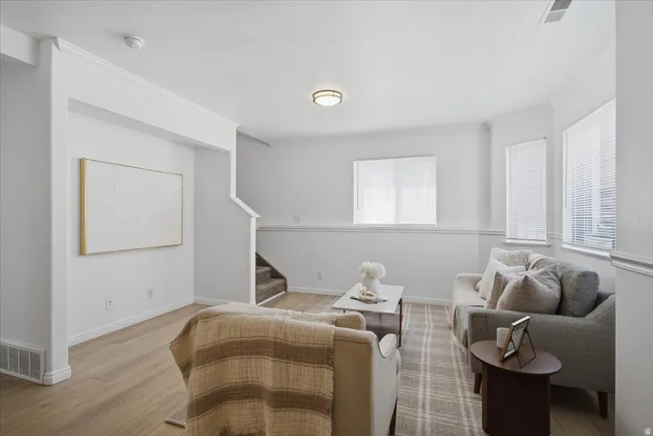 Spacious room with wood-finish flooring, multiple windows, and a carpeted staircase