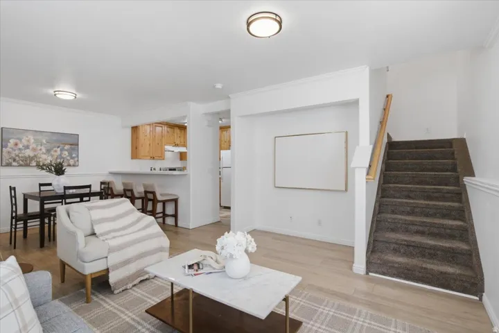 Open concept living area featuring wood-finish flooring, recessed lighting, and a staircase with a wood handrail