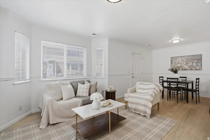 Light wood-finish flooring, white walls with chair rail molding, and multiple windows with horizontal blinds