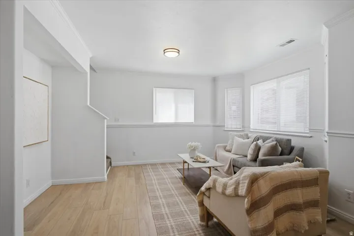 Recessed windows with blinds, wood-finish flooring, white painted walls, and overhead lighting