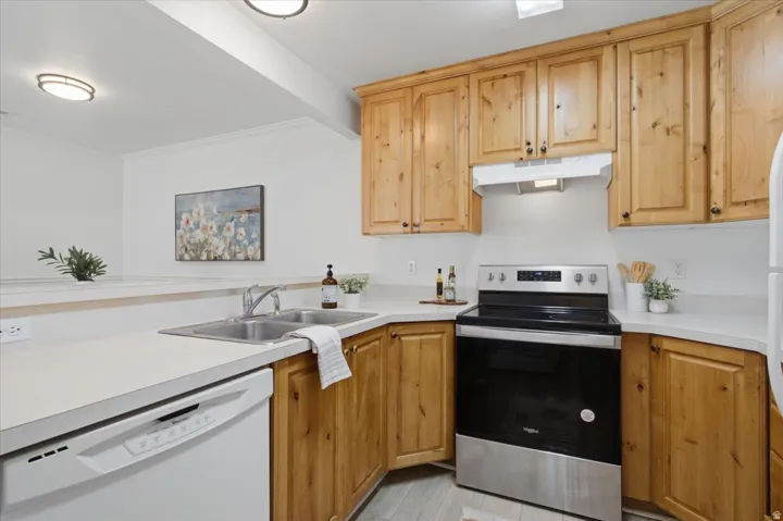 Kitchen featuring wood-finish cabinetry, white countertops, a stainless steel range, and a built-in dishwasher