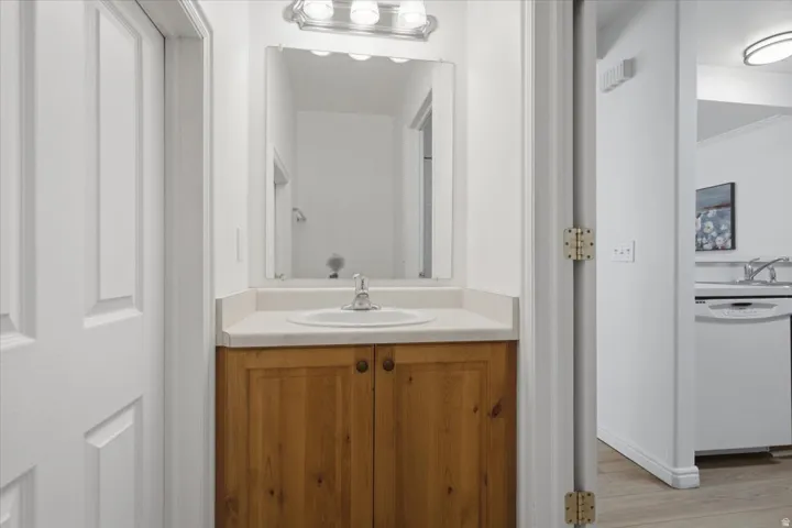 Wood-finish vanity with a single basin sink and a mirror with overhead lighting