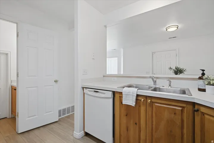 Kitchen area with wood-finish cabinetry, a double basin stainless steel sink, and light-toned countertops