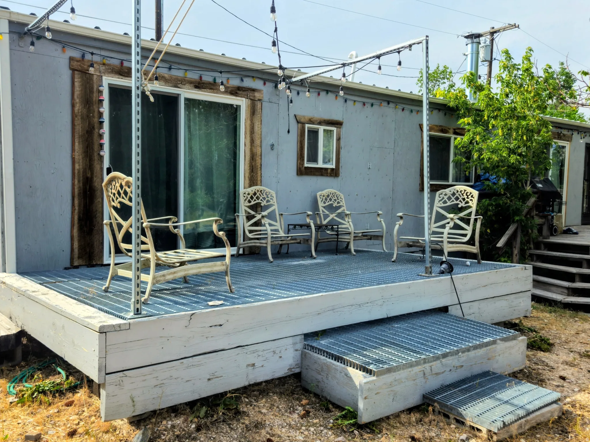 Expansive exterior deck with metal grate steps and sliding glass door entry