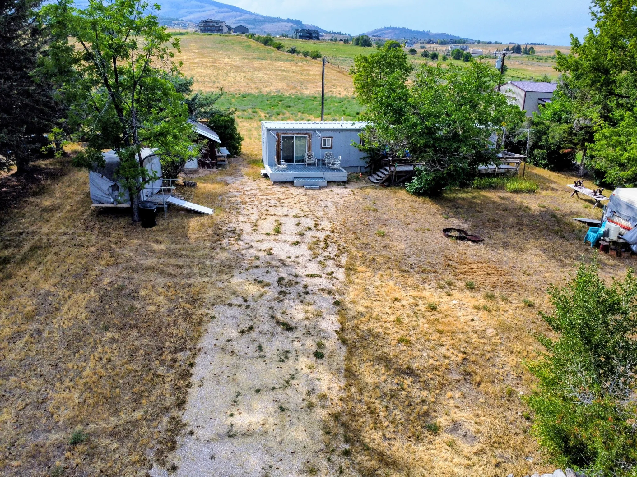 Expansive property featuring a gravel-covered pathway, surrounding natural terrain, and mature trees