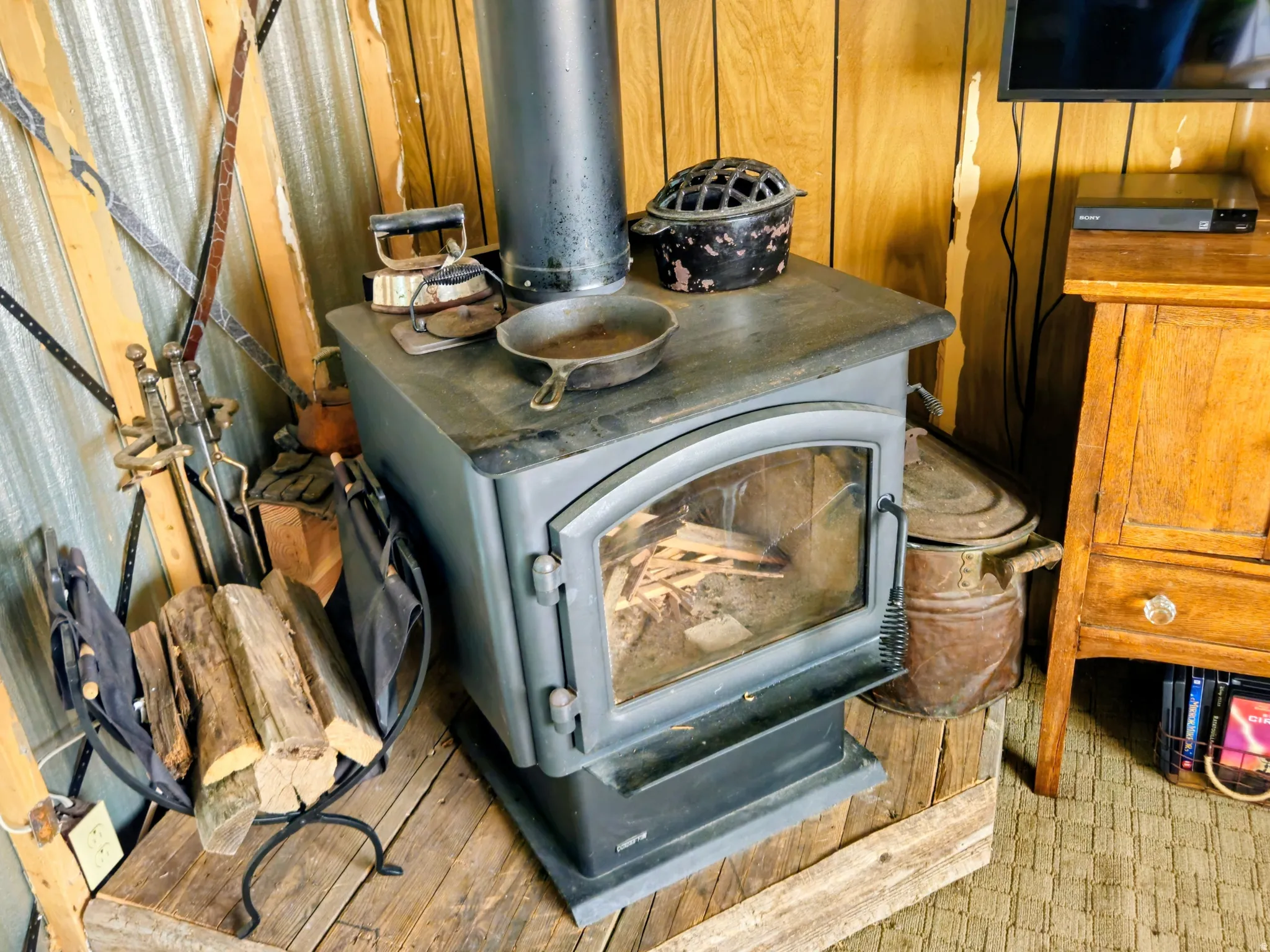 Wood-paneled wall with a freestanding wood-burning stove on a raised wooden platform