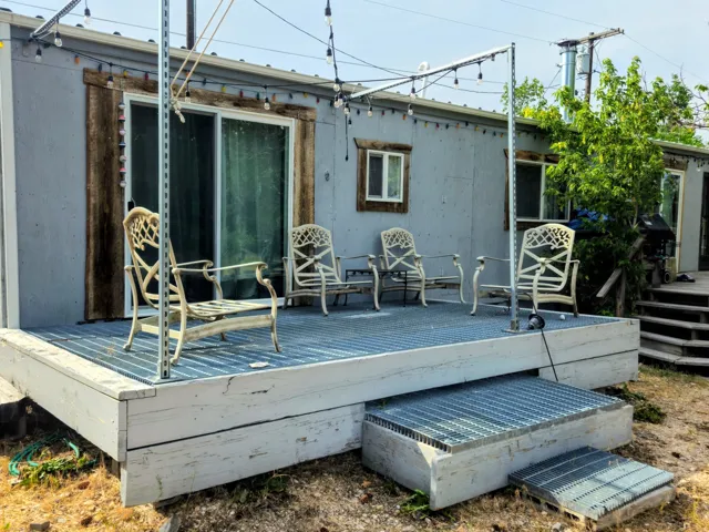 Expansive exterior deck with metal grate steps and sliding glass door entry