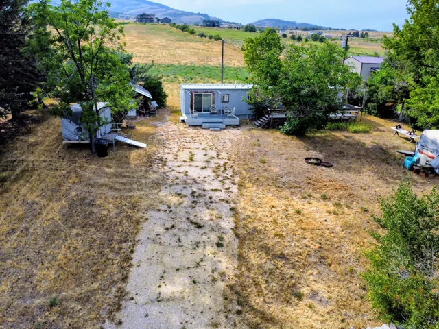 Expansive property featuring a gravel-covered pathway, surrounding natural terrain, and mature trees