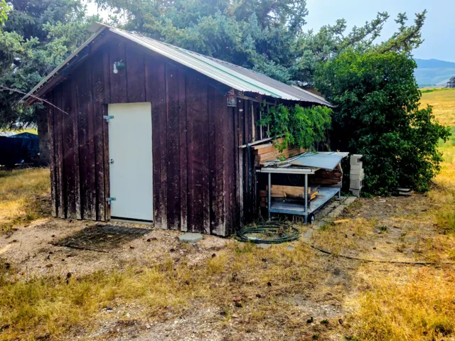 Wood-sided outbuilding with a white entry door and a metal roof