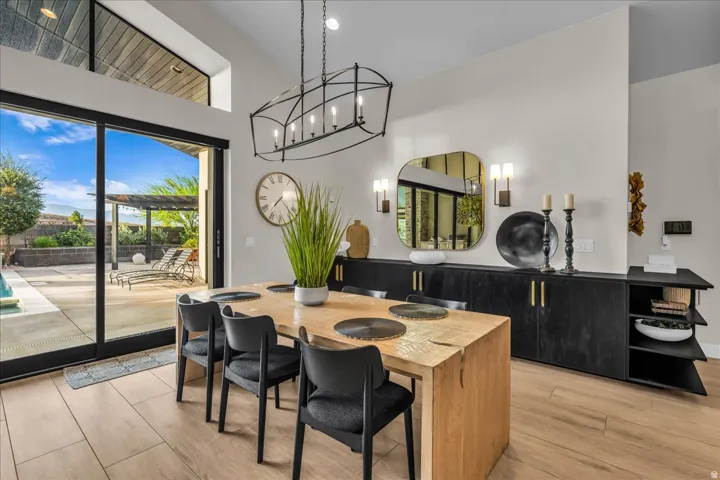 Vaulted ceiling, full-height sliding glass door, wood-finish flooring, linear chandelier, and built-in cabinetry