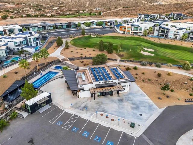 Clubhouse building featuring rooftop solar panels, multiple swimming pools, a spa, and a golf course