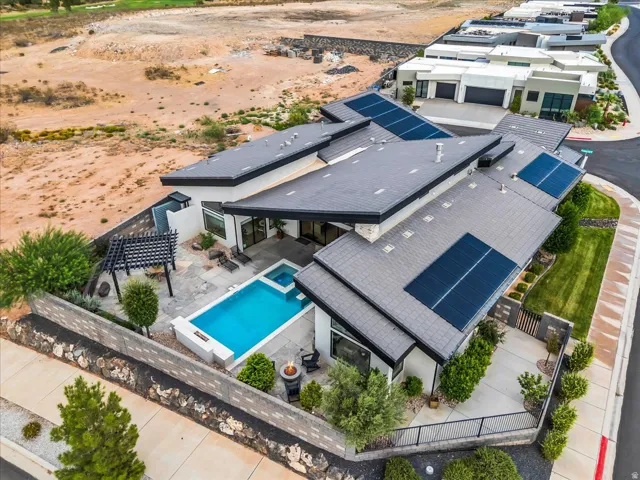 Contemporary exterior with multiple solar panel arrays, a geometric pool with an integrated spa, an outdoor fire pit, and a shaded pergola