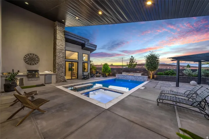 Outdoor living area with a built-in grill and counter space, a swimming pool, and an integrated spa