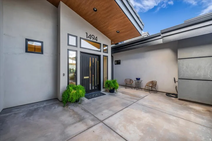 Modern exterior with a wood-finish soffit, custom entrance door, and surrounding transom windows