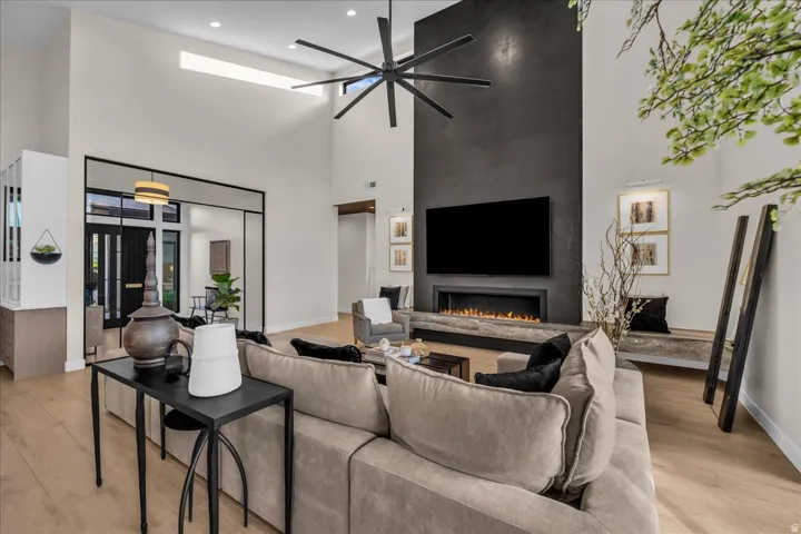 Vaulted ceilings with recessed lighting, wood-finish flooring, and a linear fireplace set within a dark accent wall