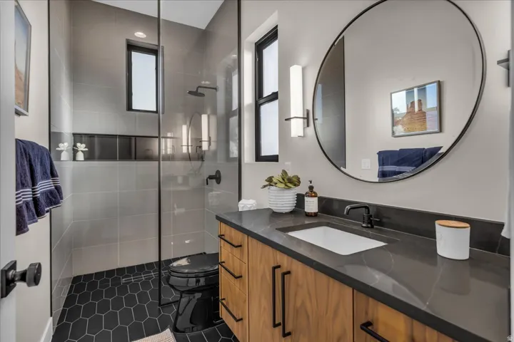 Enclosed shower with gray wall tile and black hexagonal floor tile