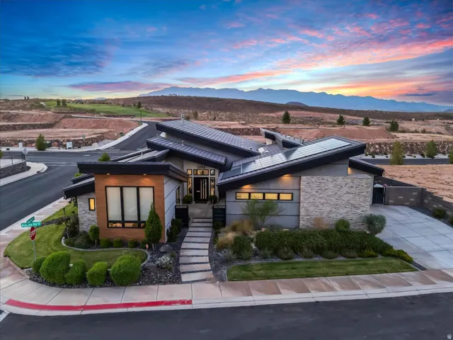Modern architectural design featuring varied rooflines, solar panel arrays, stone and wood-finish exterior accents, and a tiered concrete walkway
