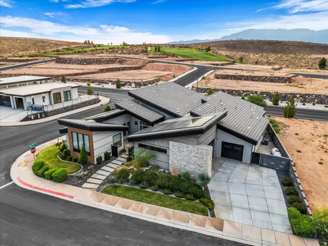 Modern exterior with a multi-level roofline, integrated solar panels, a stone accent wall, and a concrete paver driveway