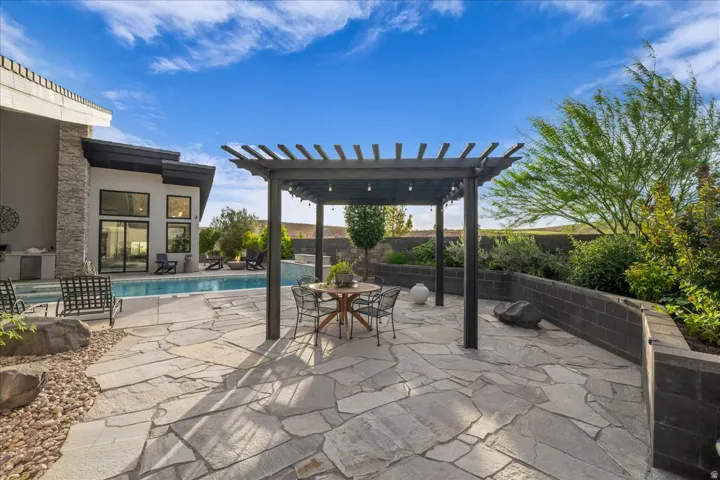 Irregular flagstone patio featuring a dark wood pergola with string lighting