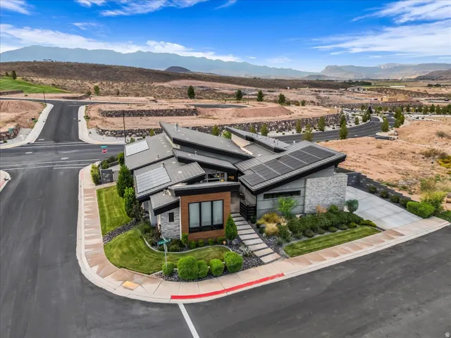 Contemporary architectural design featuring a multi-planar roofline, stone and wood-panel accents, integrated solar panels, and a manicured landscape with stepping stone pathways
