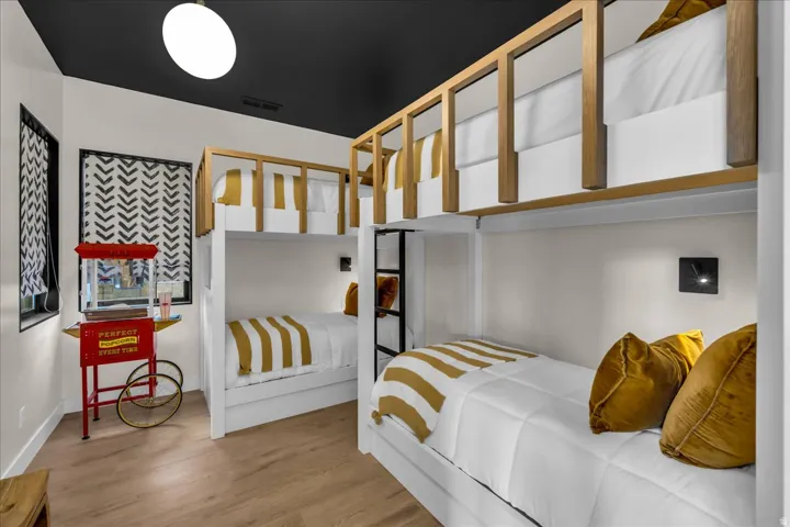 Built-in bunk beds with wood-finish detailing, recessed wall sconces, wood-finish flooring, and a contrasting dark ceiling with an overhead light fixture