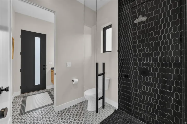 Walk-in shower with black hexagonal tile surround and matte black fixtures