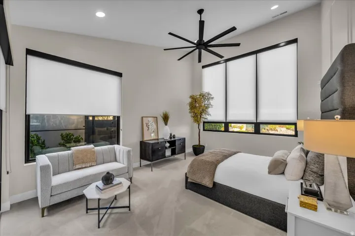 Recessed lighting, sloped ceiling, wide windows with roller shades, and a ceiling fan