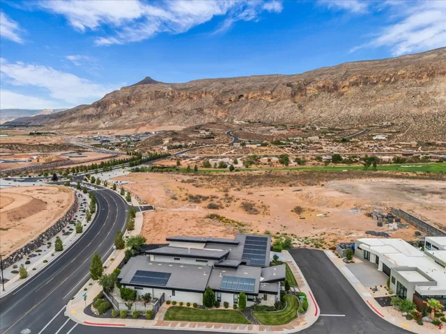 Modern-style residence with multiple roof-mounted solar panels, situated on a corner lot with landscaped grounds