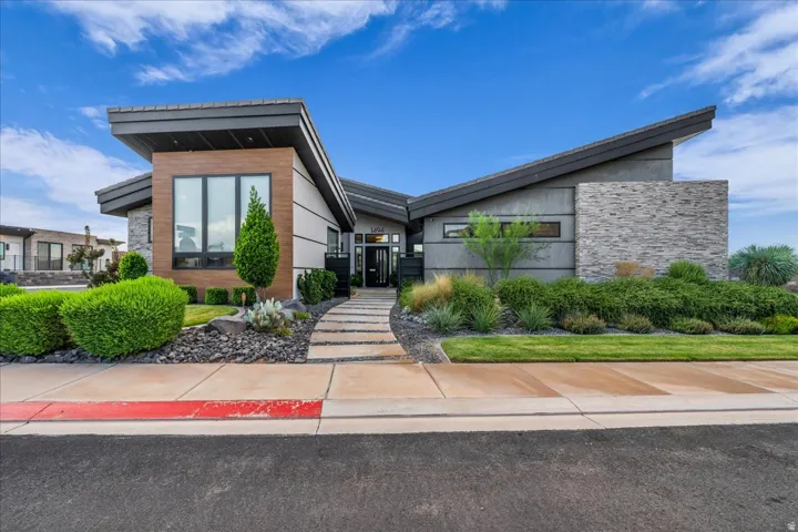Modern exterior with an angled roofline, stone accents, wood-finish paneling, and an integrated xeriscape landscape