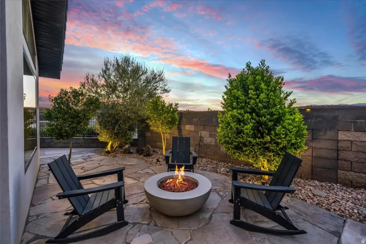 Flagstone patio with a built-in fire pit, surrounded by mature landscaping and a stone block retaining wall