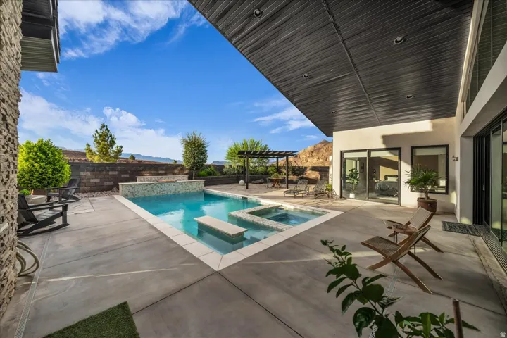 Concrete patio featuring a swimming pool, integrated spa, and a textured stone accent wall