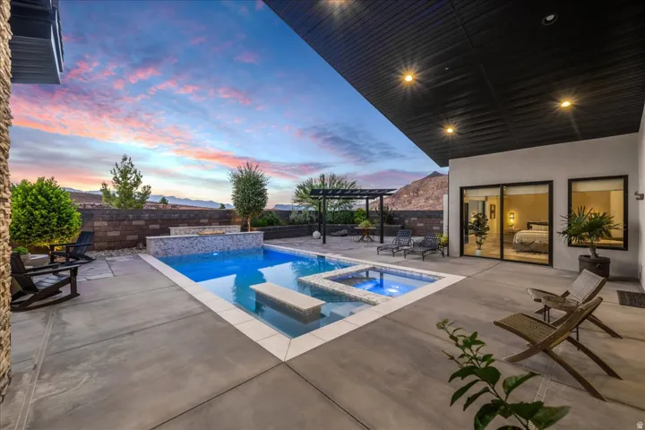 Outdoor living space with a swimming pool, integrated spa, and concrete patio