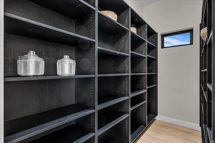 Expansive built-in shelving with dark wood-finish, light wood-finish flooring, and a rectangular window
