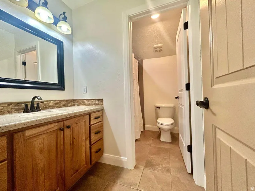 Wood-finish vanity with a light-colored countertop and tile backsplash