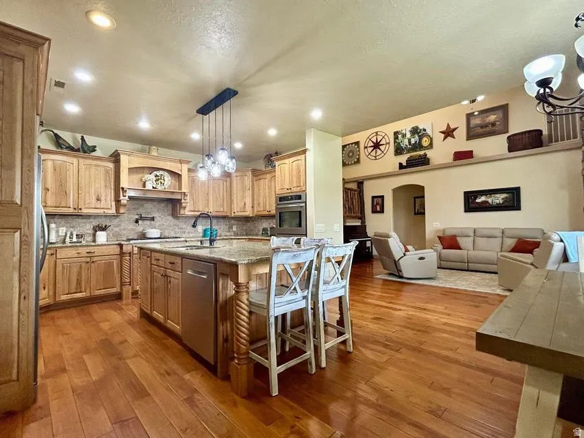 Spacious kitchen featuring wood-finish cabinetry, a large center island with a stone countertop, and stainless steel appliances