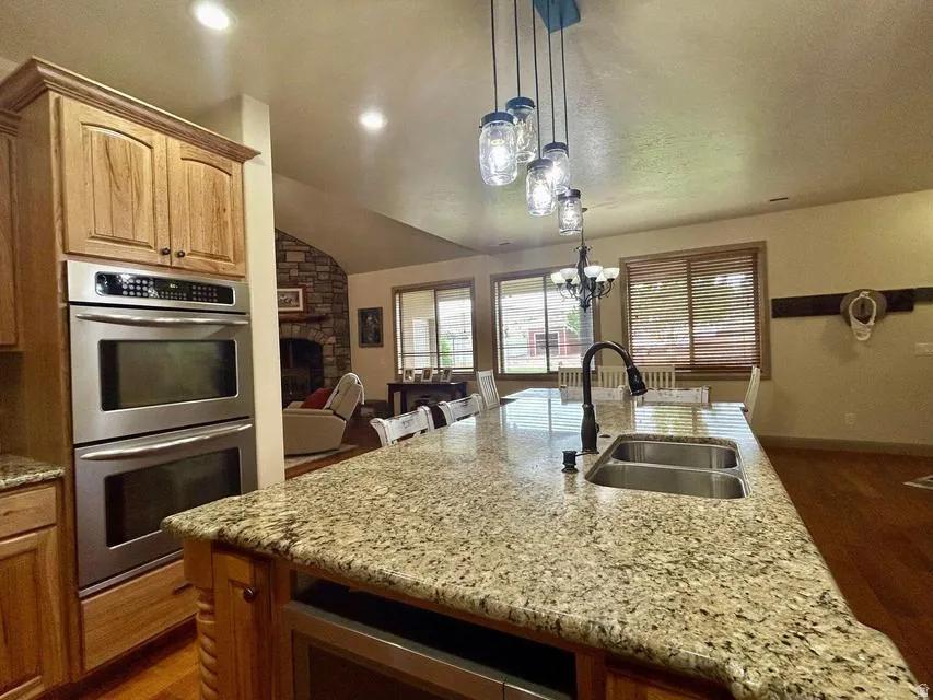 Gourmet kitchen featuring a large island with a double basin sink, granite countertops, and stainless steel double ovens