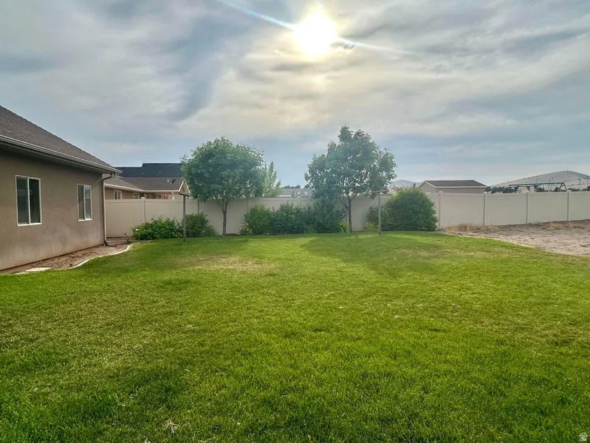 Expansive green lawn with mature trees, bordered by privacy fencing