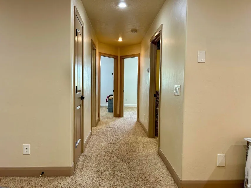 Hallway with carpet flooring, recessed lighting, and wood-finish trim around doorways