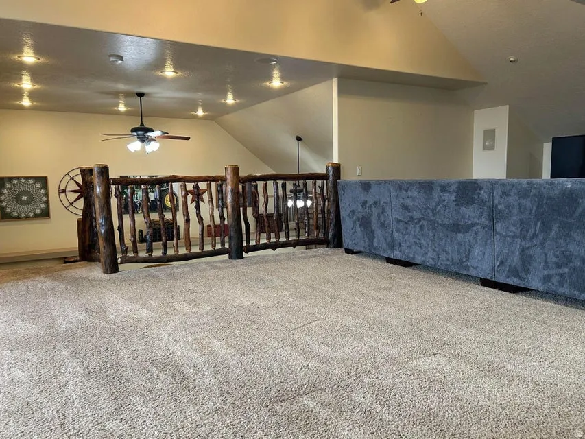 Loft area featuring vaulted ceilings, recessed lighting, a ceiling fan, and rustic wood railing