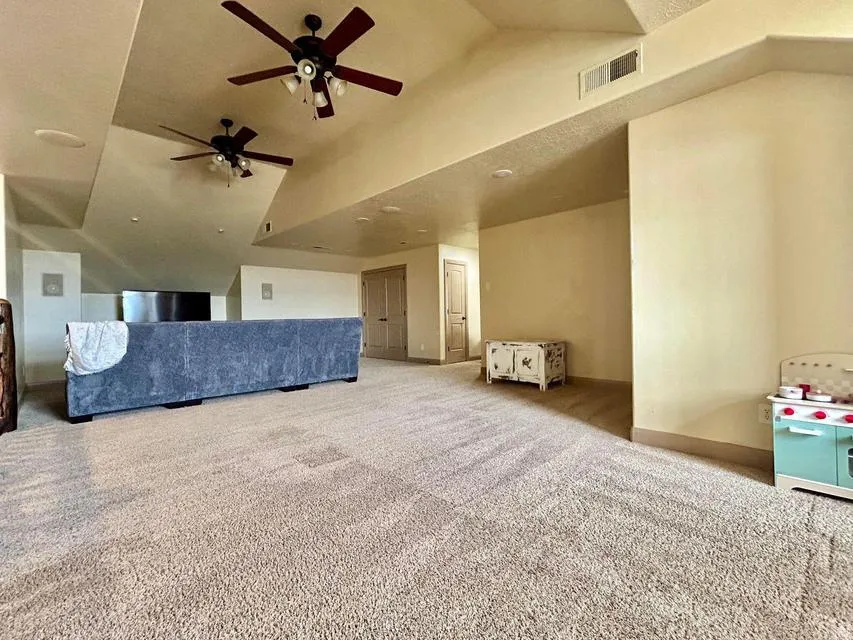Vaulted ceilings with recessed lighting, two ceiling fans, and neutral-toned carpeting