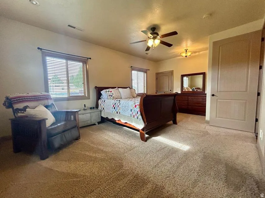 Carpeted room featuring multiple windows with blinds, a ceiling fan with integrated lighting, and recessed ceiling lighting
