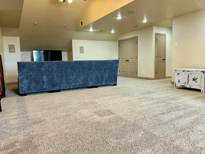 Expansive carpeted area with recessed lighting, integrated wall speakers, and multiple built-in doors